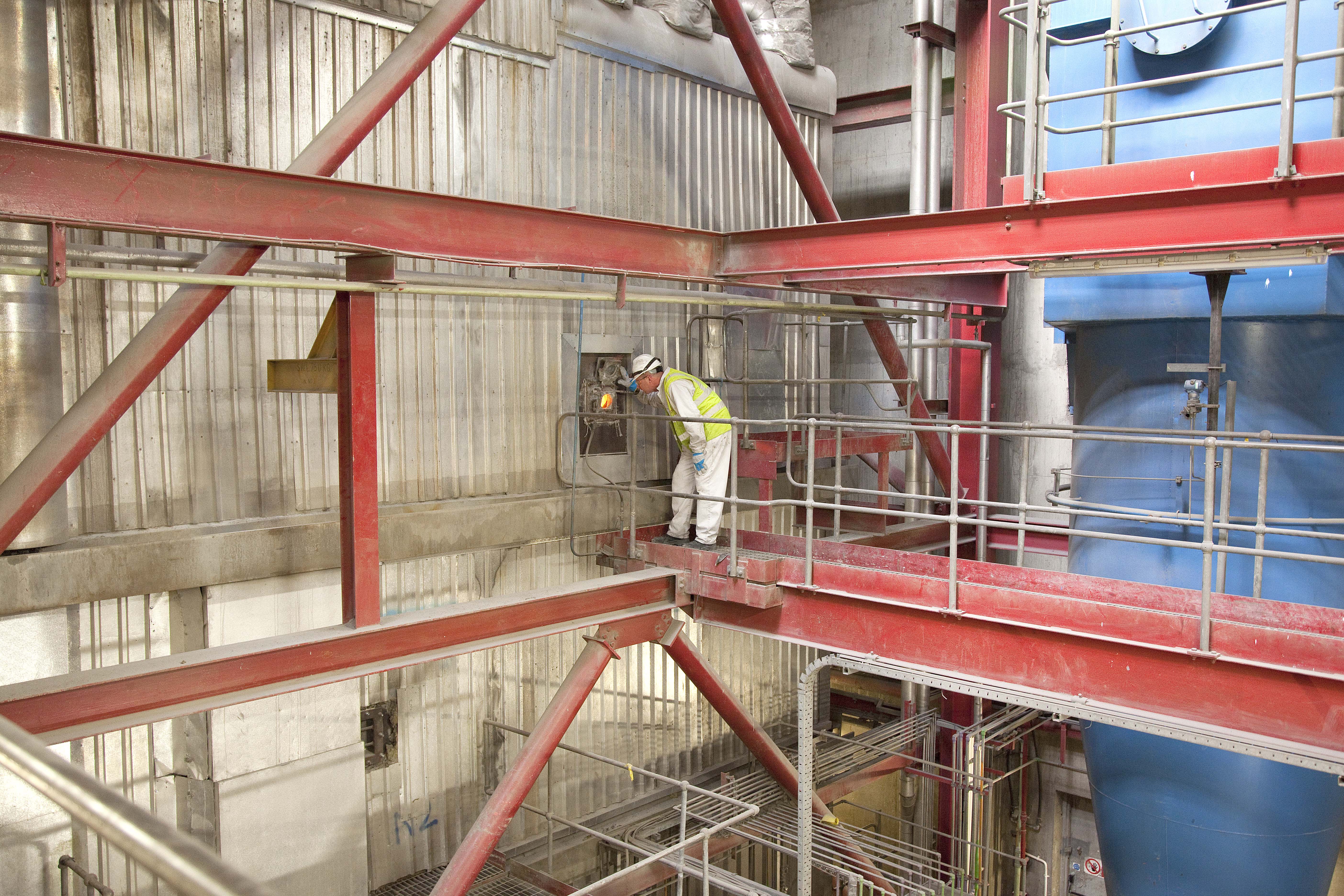 Photo showing a worker looking through a window into the incinerator